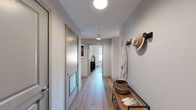 This 2-bedroom, 1-bathroom residence is designed with a modern, functional layout that makes efficient use of its space. The entry hallway sets a clean, contemporary tone with light wood-style flooring, globe pendant lighting, and a built-in bench with wall hooks — providing a practical and welcoming arrival experience. The flooring flows consistently throughout the unit, creating visual cohesion.

The open-concept kitchen and living area form the heart of the home. The kitchen features shaker-style cabinetry in soft gray-white tones, a white subway tile backsplash, stainless steel appliances including a range and dishwasher, and pendant lighting above a central island — offering ample prep and storage space. The adjacent living room is bright and airy, with large windows dressed in layered sheer and blackout curtains that frame urban views of the surrounding cityscape.

The generously sized primary bedroom provides a comfortable retreat, featuring light wood flooring, neutral walls, and windows that invite natural light. The second bedroom offers similar finishes with access to closet storage. The full bathroom includes a soaking tub with shower, large-format tile surround, and classic neutral finishes. Throughout the residence, a consistent palette of warm neutrals, wood tones, and modern fixtures creates a cohesive and inviting atmosphere.