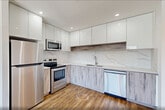 Located at 141 South Harrison Street in East Orange, NJ, this thoughtfully designed studio unit offers a clean, modern aesthetic with an efficient and well-organized layout. The open-concept kitchen and living area serves as the heart of the space, bathed in natural light from a wide, multi-pane window that frames views of the surrounding East Orange neighborhood. Light-toned hardwood-style flooring extends throughout, complementing the bright white walls and creating a warm, cohesive atmosphere. The kitchen is outfitted with high-gloss white upper cabinetry, wood-toned lower cabinets, a striking marble-effect backsplash, and a full suite of stainless steel appliances including a refrigerator, electric range, microwave, and dishwasher — delivering both style and full functionality. The bathroom features a soaking tub and shower combination with a standout tiled surround, accented by an eye-catching mosaic stone centerpiece in warm earth tones, adding a touch of elegance. A dedicated closet provides convenient storage, while an in-unit laundry area adds everyday practicality. Recessed lighting and flush-mount ceiling fixtures ensure a well-lit interior throughout the day and evening. The overall ambiance is clean, contemporary, and move-in ready.