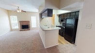 This single-floor residence offers a functional and comfortable layout centered around an open-concept living and kitchen area. The living room is a welcoming space highlighted by a classic brick fireplace flanked by windows that allow natural light to fill the room. Soft carpeting, a ceiling fan, and a textured ceiling complete the relaxed ambiance of this area.

The kitchen flows seamlessly from the living space via a peninsula-style breakfast bar with a granite-look countertop. Dark espresso cabinetry contrasts with the light countertops, and the kitchen is fully equipped with black appliances including a refrigerator, range, built-in microwave, and dishwasher. A double-basin stainless steel sink sits beneath a window, and warm hardwood-style flooring ties the space together. A louvered bi-fold door leads to a dedicated laundry area.

The bedroom is generously sized with plush carpeting, a ceiling fan, and access to a spacious walk-in closet. Two bathrooms serve the residence — each featuring dark vanity cabinetry with granite-look countertops. One bathroom includes hardwood-style flooring and a tub/shower combination, while the second is finished with white tile surrounding the tub and shower and a well-lit vanity mirror with built-in shelving.