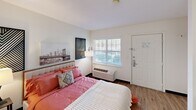 Located at 4515 Apex Hwy in Durham, NC, this efficiently designed studio-style unit offers a thoughtful single-floor layout that maximizes every square foot. The main living area serves as the bedroom, featuring hardwood-style flooring, a large window with blinds that invites natural light, and a wall-mounted PTAC unit for personalized climate control. The space comfortably accommodates a full-size bed alongside a wooden dresser, providing practical storage within the living area.

A built-in counter with cabinetry acts as a natural divider between the sleeping area and the kitchenette, doubling as a convenient prep or dining surface. The kitchenette is outfitted with white cabinetry, a refrigerator, a sink, and overhead lighting, offering essential cooking functionality in a compact footprint.

The bathroom is clean and straightforward, featuring wood-style flooring, a wide vanity with an integrated sink, a large framed mirror with overhead lighting, and a toilet — all presented in a bright, neutral palette.

Throughout the unit, the white walls and consistent flooring create a cohesive, airy feel. This space is well-suited for individuals seeking a practical, self-contained living environment in the Durham, NC area.