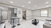 Located at 66 Cheney Dr in Storrs Mansfield, CT, this single-floor unit offers a thoughtfully designed layout with a cohesive, contemporary aesthetic throughout. Marble-look porcelain tile flooring flows consistently across all areas, contributing to a clean, bright atmosphere.

The open living area is illuminated by recessed ceiling lighting and features neutral white paneled walls accented with gray trim, creating a polished, modern look. A private entry door with a sunburst transom window provides natural light to the space. The living area connects directly to a kitchenette bar with granite countertops and bar seating, as well as a fully equipped galley-style kitchen outfitted with slate-blue cabinetry, granite countertops, a subway tile backsplash, stainless steel appliances including a range and full-size refrigerator, and a dedicated entry door.

The bedroom is a well-proportioned, enclosed room with small windows that allow natural light and feature gray-framed cabinetry for storage. The bathroom is elegantly finished with wood-tone and neutral tile walls, a glass-enclosed shower, a gray vanity with a vessel sink, and chrome fixtures, lending a spa-like quality to the space. The overall design is modern, functional, and well-maintained throughout.