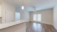 Located at 120 Buckhill Village Dr in Burlington, NC, this single-story 2-bedroom, 2-bathroom home offers a thoughtfully designed layout across a comfortable footprint. The open-concept living, dining, and kitchen area serves as the heart of the home, where rich wood-look flooring flows throughout. The kitchen is outfitted with stainless steel appliances — including a refrigerator, range, and microwave — white shaker-style cabinetry extending to the ceiling, granite-style countertops, and a peninsula island with pendant lighting overhead. The living area features a ceiling fan and French doors that fill the space with natural light and provide outdoor access. The primary bedroom offers a generous layout with plush carpeting and a spacious walk-in closet complete with wire shelving systems. A second bedroom, also carpeted, provides a clean and versatile space. Both bathrooms include tub-shower combinations with curved curtain rods. A dedicated laundry room houses a full-size side-by-side washer and dryer with overhead wire shelving. With seven closets throughout, storage is ample. The home's clean, neutral palette and modern finishes create a bright, move-in-ready atmosphere throughout.