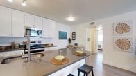 This well-designed 2-bedroom, 2-bathroom residence is laid out across a single floor, offering a seamless and functional living experience. The open-concept kitchen serves as the heart of the home, featuring white shaker-style cabinetry, a classic white subway tile backsplash, stainless steel appliances including a range and built-in microwave, and a generous peninsula with a dark quartz-style countertop that provides ample prep space and casual bar seating. The kitchen flows naturally into the living area, creating an inviting, connected space ideal for everyday living and entertaining. The interiors are finished with light-toned flooring that extends throughout, complemented by crisp white walls that enhance the sense of brightness and openness. Recessed and flush ceiling fixtures provide consistent lighting throughout. The bedrooms are accessible via a central hallway, offering privacy and separation from the main living areas. The overall ambiance is clean, modern, and move-in ready, with a neutral palette that provides a versatile backdrop for a variety of décor styles. This thoughtfully laid-out residence balances comfort and functionality in a contemporary package.