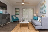 This single-floor residence offers a thoughtfully designed layout with a cohesive modern aesthetic throughout. The living room serves as a welcoming central space, featuring wood-style flooring, crown molding, a ceiling fan, and a large sliding glass door dressed with vertical blinds that fills the room with natural light and provides access to the outdoors.

The kitchen is well-equipped and stylish, showcasing charcoal gray cabinetry, a gray subway tile backsplash, light quartz-style countertops, and stainless steel appliances including an electric range and refrigerator. A stainless steel sink and ample counter space make it both functional and attractive.

The primary bedroom is a spacious retreat with plush wall-to-wall carpeting, a ceiling fan, and a window with blinds. The second bedroom mirrors this comfortable style, also featuring carpet flooring, a natural light window, and a mirrored sliding closet door that adds depth to the room.

The bathroom is clean and functional, featuring dark cabinetry with a light countertop vanity, a large mirror with a lighted fixture above, and a tub-shower combination enclosed by frosted sliding glass doors set against classic white subway tile. Wood-style flooring completes the bathroom's polished look. The space presents a consistent, modern color palette of grays, whites, and warm accent tones throughout.