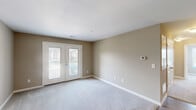 Located at 142 Wolfetrail Rd in Greensboro, NC, this single-floor, 3-bedroom, 2-bathroom home offers a functional and comfortable layout designed for everyday living. The open-concept kitchen and living area serves as the heart of the home, featuring rich dark cabinetry, granite-look countertops, a peninsula island with a built-in sink, pendant lighting, and white appliances including a range, microwave, and refrigerator. Durable hardwood-style flooring runs throughout the kitchen and main living areas, adding warmth and visual continuity. The living room is bright and inviting, highlighted by double French doors that open to a private balcony with outdoor views, allowing natural light to fill the space. The three bedrooms are carpeted for comfort, each finished with neutral warm-toned walls and ample natural light from well-positioned windows. The spacious primary bedroom includes a double-door closet and generous floor space. The bathrooms are clean and efficient, with one featuring a walk-in shower with built-in shelving and chrome fixtures. A hallway with hardwood-style flooring connects the bedrooms and bathrooms, completing this well-organized and move-in-ready home.