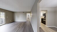 Located at 725 Mansion Cir in Chattanooga, TN, this single-story home offers a well-organized, functional layout designed for comfortable everyday living. The main living area is generously sized, featuring warm-toned hardwood-style flooring, neutral gray walls, and a textured ceiling. A hallway connects the living space to the private rooms, maintaining a clear and practical flow throughout the home.

The kitchen is efficiently designed with crisp white cabinetry extending to the ceiling, speckled countertops, a stainless steel sink, and black appliances including a full-size refrigerator, range, and dishwasher. A pass-through window connects the kitchen to the living area, enhancing the open feel. An adjacent dining area with a pendant light offers a defined space for meals.

The bedrooms feature plush carpet flooring and ceiling fans, with one bedroom offering direct access to a bathroom equipped with a white vanity, speckled countertop, and a full tub-shower combination. Closets with louvered doors and built-in rods provide ample storage. A dedicated laundry area houses the water heater and washer/dryer hookups. Sliding glass doors lead to a private outdoor patio, bringing in natural light and outdoor views.