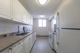 Located at 2 Kozlov Street in Barrie, Ontario, this 2-bedroom, 1-bathroom unit offers a well-organized single-floor layout with a clean, functional design throughout. Warm parquet wood flooring flows consistently across the living spaces, bedrooms, and hallways, adding a classic character to each room.

The open living area is generously proportioned, filled with natural light, and anchored by a large sliding glass door that leads directly to a private balcony with expansive outdoor views of the surrounding cityscape. A ceiling fan overhead adds to the room's comfort.

The galley-style kitchen is efficiently designed, featuring white cabinetry on both sides, laminate countertops, a double stainless steel sink, and a full suite of white appliances including a refrigerator, electric range with overhead microwave, and dishwasher.

Both bedrooms are well-sized and bright, each featuring large windows that frame wide open views — a standout feature of this elevated unit. One bedroom includes a sliding closet, while the primary bedroom offers a dedicated closet space. The bathroom is clean and straightforward, with a single vanity, mirror, and a full bathtub. A central hallway with textured ceiling connects all rooms efficiently, completing this practical and comfortable layout.