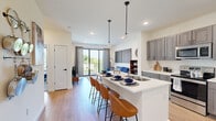 This single-floor, one-bedroom, one-bathroom unit offers a thoughtfully designed open-concept layout that maximizes its compact footprint. The kitchen and living area flow seamlessly together, anchored by a sleek white quartz island with an undermount double sink, pendant lighting, and seating for multiple bar stools — ideal for casual dining or entertaining. The kitchen features gray shaker-style cabinetry extending to the ceiling, stainless steel appliances including a French-door refrigerator, electric range, built-in microwave, and dishwasher, all set against light hardwood-style flooring that runs throughout the main living area.

The living room benefits from large sliding glass doors that open to a private balcony, allowing generous natural light and outdoor views. The bedroom offers carpeted flooring, a large window with outdoor views, and notable ceiling height, creating a comfortable and airy retreat. Multiple closet doors provide ample storage within the bedroom.

The bathroom features a clean, minimalist design with light-toned walls and hardwood-style flooring consistent with the rest of the unit. Throughout, the unit maintains a contemporary aesthetic with crisp white walls, recessed lighting, and black hardware accents that tie the design together cohesively.