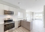 Located at 11025 26 Avenue NW in Edmonton, Alberta, this thoughtfully designed 2-bedroom, 1-bathroom unit offers a clean, modern aesthetic across a single floor. Light wood-style flooring runs throughout, complementing the neutral palette of soft whites and warm greiges that define the interior.

The kitchen is a standout feature, boasting crisp white upper cabinetry, two-tone grey lower cabinets, and bright white countertops. A full suite of stainless steel appliances — including a refrigerator, electric range, built-in microwave, and dishwasher — adds a polished, functional touch. A peninsula with an undermount sink and views into the open living area creates a connected, airy feel. Natural light flows in through multiple windows, offering pleasant outdoor views.

The primary bedroom is a comfortable, well-proportioned space with a large window overlooking the surrounding neighbourhood. Both bedrooms are served by a well-organized hallway featuring dual closets with built-in shelving, maximizing storage. The bathroom is finished with a glass-enclosed walk-in shower with marble-style tile surround and light wood-look flooring.

A dedicated hallway leads to a convenient in-suite stacked washer and dryer, adding everyday practicality. The overall ambiance is bright, clean, and move-in ready.