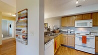 Located at 1870 N Lennox St in Olathe, Kansas, this 2-bedroom, 2-bathroom single-floor residence offers a well-organized and functional layout. The open-concept kitchen and living area serves as the heart of the home, where warm honey-toned wood cabinetry, dark granite-style countertops, and white appliances — including a range, microwave, dishwasher, and refrigerator — create a practical and inviting kitchen. Hardwood-style flooring runs throughout the main living areas, adding warmth and continuity. The living room is bright and welcoming, featuring a sliding glass door that opens to a private outdoor patio, filling the space with natural light. The primary bedroom offers carpeted flooring, a window with outdoor views, a textured ceiling, and direct access to one of the two bathrooms — providing a convenient en-suite feel. The second bedroom also features carpeting, natural light from a window, and an adjacent closet. Both bathrooms are thoughtfully designed with wood vanities, white fixtures, and overhead storage. Additional features include a dedicated laundry area, utility room, and three closets for ample storage throughout the residence.