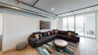 Located on Beach Avenue in the Marina del Rey neighborhood of Los Angeles, this contemporary single-floor residence showcases a clean, modern design with industrial-inspired accents throughout. Exposed metal ductwork and track lighting run along the ceilings, adding an urban loft character to the otherwise minimalist interior.

The open-concept living, dining, and kitchen area forms the heart of the unit. The kitchen is outfitted with stainless steel appliances, including a gas range, built-in microwave, side-by-side refrigerator, and dishwasher. Two-tone cabinetry pairs white upper cabinets with wood-grain lower units, complemented by a subway tile backsplash and a undermount sink. Light hardwood flooring extends throughout the common areas, connecting seamlessly to the dining and living spaces. The living room features floor-to-ceiling windows that invite abundant natural light and offer views of the surrounding area.

The bedrooms are carpeted and bright, each offering sliding glass doors to outdoor areas and ample closet space. The bathrooms are finished with white rectangular tile, featuring both a glass-enclosed walk-in shower and a separate soaking tub option. A dedicated in-unit laundry area with a stacked washer and dryer adds everyday convenience near the entryway.
