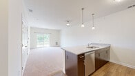 Located at 457 Dutch Meadows Ln in Schenectady, NY, this single-floor residence offers a clean, modern design with a bright and open layout throughout. The heart of the home is an open-concept kitchen and living area, where rich dark-cabinetry contrasts beautifully with light granite countertops on a functional center island equipped with a stainless steel sink. Pendant lighting above the island adds a contemporary touch, while a full suite of stainless steel appliances—including a range, microwave, and refrigerator—completes the kitchen. Hardwood flooring anchors the kitchen area, transitioning into plush wall-to-wall carpeting across the spacious living room, which is bathed in natural light from a large sliding glass door leading to a private balcony with outdoor views. The generously sized bedrooms feature soft carpeting and ample closet space, with one bedroom offering its own direct access to the balcony. The bathroom is well-appointed with a wide vanity, white cabinetry, a framed mirror, and a combined tub and shower enclosure. Throughout the residence, neutral tones and clean white walls create a welcoming, move-in-ready atmosphere.