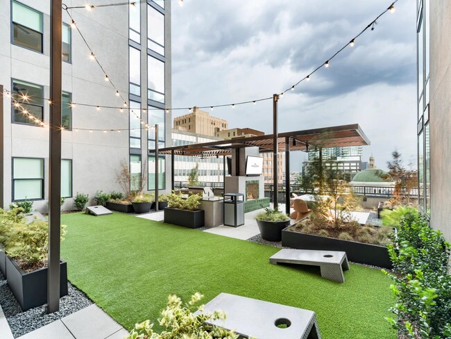 Relájese en la terraza del jardín de Modera St. Paul con vistas al horizonte, juegos de césped y espacios acogedores perfectos para reunirse en el corazón de Dallas. - Modera St. Paul