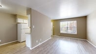 This thoughtfully laid-out 1-bedroom, 1-bathroom single-floor unit offers a comfortable and functional living experience. Light wood-toned luxury vinyl plank flooring flows consistently throughout, providing a clean and cohesive aesthetic across every room.

The open-concept living room is bright and welcoming, featuring a large window with blinds that allows ample natural light to fill the space. Warm neutral-toned walls complement the light flooring, creating an inviting atmosphere throughout.

The kitchen is positioned adjacent to the living area and is separated by a half-wall with a breakfast bar counter. It is equipped with white cabinetry, a double stainless steel sink, dark laminate countertops, a white refrigerator, and a white electric range. Upper cabinets provide generous storage, and a window above the sink area adds natural light to the workspace.

The spacious primary bedroom features a ceiling fan with light fixture, a natural light-admitting window, and an expansive set of double bi-fold closet doors revealing well-organized closet space with multiple compartments — offering substantial storage capacity.

The bathroom includes a wide vanity with dark countertops, a white sink, and a large mirror, maintaining the same neutral color palette found throughout the unit. The layout of the home is efficient and practical, making excellent use of every area available.