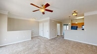 Located at 7160 Oxfordshire Blvd in Noblesville, Indiana, this one-bedroom, one-bathroom unit offers a well-organized and functional layout across a single floor. The open-concept living and kitchen area serves as the heart of the home, featuring plush wall-to-wall carpeting, crown molding, and a ceiling fan with light fixture overhead. The kitchen is equipped with warm-toned wood cabinetry, black appliances including a refrigerator, range, and microwave, a stainless steel sink, and light wood-look vinyl flooring that extends throughout the wet areas. The spacious bedroom features soft carpeting and a sliding glass door that opens to a private balcony overlooking a scenic outdoor view, allowing for an abundance of natural light. A large picture window in a secondary area also invites natural light and garden views. The full bathroom features wood-toned vanity cabinetry with a white countertop, a mirror, and durable wood-look vinyl flooring. A dedicated utility room provides built-in shelving and laundry hookups, offering generous storage and organization options. Three closets are distributed throughout the unit. Carpeted stairs with a wooden handrail complete the interior, contributing to a cozy and cohesive aesthetic throughout the home.