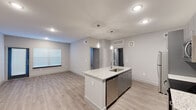 Located at 10742 Freehill Street in Houston, TX, this single-story unit presents a clean, contemporary design with thoughtful finishes throughout. The open-concept layout connects the kitchen and living areas seamlessly, creating a bright and functional living environment.

The kitchen serves as a central highlight, featuring a large island with granite countertops, an undermount sink, and stylish pendant lighting overhead. Gray flat-front cabinetry lines the walls, complemented by a full suite of stainless steel appliances, including a refrigerator, electric range, microwave, and dishwasher. Light wood-style vinyl flooring extends through the kitchen and living areas, enhancing the modern aesthetic.

The living space is open and well-lit, with a window allowing natural light to filter in and a front entry door providing direct access. The neutral gray walls and clean baseboards maintain the unit's contemporary character throughout.

The bedrooms feature plush carpeting, ceiling fans, and windows with blinds that allow for natural light control. Each room offers a comfortable, quiet retreat with ample wall space.

The bathroom includes a tub-shower combination with large-format tile surround, a granite-topped vanity with gray cabinetry, and wood-style flooring, maintaining consistent finishes seen throughout the unit.