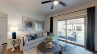 This single-floor, one-bedroom, one-bathroom unit offers a thoughtfully designed open-concept layout that seamlessly connects the kitchen, dining, and living areas. The kitchen is a standout feature, showcasing dark espresso cabinetry, granite countertops, a subway tile backsplash, stainless steel appliances, and a peninsula island with pendant lighting overhead — ideal for both cooking and casual dining. Wood-style flooring runs throughout the main living areas, adding warmth and continuity.

The living room is bright and inviting, anchored by crown molding, a ceiling fan, and a large sliding glass door that opens to a private balcony with outdoor seating, allowing natural light to fill the space. Built-in shelving along one wall provides functional storage and display options.

The bedroom is a serene retreat finished with plush carpeting, a ceiling fan, and a generously sized window dressed with sheer curtains that invite soft natural light. The full bathroom features dark cabinetry with granite countertops, wood-style flooring, and a shower-tub combination. Throughout the unit, neutral tones and clean finishes create a cohesive, modern aesthetic.