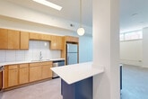 Located at 8 S Sixth St in Council Bluffs, Iowa, this one-bedroom, one-bathroom unit offers a thoughtfully designed single-floor layout. The kitchen serves as a standout feature, showcasing warm maple cabinetry, a classic white subway tile backsplash, and a full suite of stainless steel appliances including a refrigerator, dishwasher, range, and microwave. A striking cobalt blue island with a crisp white countertop anchors the space, complemented by a stylish globe pendant light suspended from the ceiling, adding a modern touch. Soft carpeting flows throughout the living areas, creating a warm and cohesive feel. A long, clean hallway with recessed lighting connects the main living areas to the private spaces, maintaining a sense of order and flow. The bedroom is a comfortable, carpeted retreat featuring a double closet and horizontal windows that allow natural light to filter in. The bathroom is clean and functional, offering a tub-shower combination, a wooden vanity with a white countertop, and a well-lit mirror above. Neutral tones and clean white walls throughout the unit create a bright, move-in-ready atmosphere that is both practical and inviting.