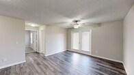 Located at 1605 E Hines St in Republic, Missouri, Unit C204 is a thoughtfully designed single-floor residence that combines functional living spaces with clean, modern finishes throughout. The kitchen is a standout feature, equipped with stainless steel appliances including an electric range and refrigerator, crisp white cabinetry offering ample storage, laminate countertops, and a stainless steel sink. Light wood-look vinyl plank flooring ties the kitchen together with a fresh, contemporary feel. The open living area extends the sense of space, featuring the same wood-look flooring, neutral wall tones, a ceiling fan, and French doors that invite natural light into the room. An additional open area provides flexible space, also finished with wood-look plank flooring and soft neutral walls. The bedrooms are carpeted for comfort, each featuring ceiling fans, natural light from windows with blinds, and closet space — one bedroom includes a dedicated walk-in closet. The bathroom is finished with a white vanity, laminate countertop, and brushed nickel fixtures beneath a well-lit vanity mirror. A dedicated in-unit laundry closet houses a full-size washer and dryer, adding everyday convenience. Textured ceilings are consistent throughout the unit, contributing to its classic residential character.