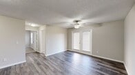 Located at 1605 E Hines St in Republic, Missouri, Unit C204 is a thoughtfully designed single-floor residence that combines functional living spaces with clean, modern finishes throughout. The kitchen is a standout feature, equipped with stainless steel appliances including an electric range and refrigerator, crisp white cabinetry offering ample storage, laminate countertops, and a stainless steel sink. Light wood-look vinyl plank flooring ties the kitchen together with a fresh, contemporary feel. The open living area extends the sense of space, featuring the same wood-look flooring, neutral wall tones, a ceiling fan, and French doors that invite natural light into the room. An additional open area provides flexible space, also finished with wood-look plank flooring and soft neutral walls. The bedrooms are carpeted for comfort, each featuring ceiling fans, natural light from windows with blinds, and closet space — one bedroom includes a dedicated walk-in closet. The bathroom is finished with a white vanity, laminate countertop, and brushed nickel fixtures beneath a well-lit vanity mirror. A dedicated in-unit laundry closet houses a full-size washer and dryer, adding everyday convenience. Textured ceilings are consistent throughout the unit, contributing to its classic residential character.