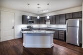 This single-story residence in Memphis, Tennessee offers a thoughtfully designed layout across two bedrooms and two full bathrooms. The kitchen serves as a central highlight, featuring rich dark-stained cabinetry extending to the upper walls, granite countertops, and a large peninsula island that provides additional prep space and a natural gathering point. Stainless steel appliances, including a range, microwave, dishwasher, and refrigerator, are complemented by track lighting and elegant pendant fixtures overhead. Hardwood-style flooring runs throughout the kitchen and living areas, adding warmth and visual continuity.

The living area benefits from natural light provided by French doors and windows fitted with blinds, creating a bright and open atmosphere. Both bedrooms are carpeted for comfort, with neutral walls and ceiling fans. One bedroom features a window that allows natural light to fill the space.

Each of the two bathrooms includes a tub-shower combination with built-in shelving, hardwood-style flooring, dark-stained vanity cabinetry with granite countertops, and chrome fixtures, maintaining a consistent design aesthetic throughout the home.
