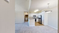 Located at 1600 Woodmeadow Ct in San Jose, California, this thoughtfully designed 2-bedroom, 2-bathroom single-floor residence offers a functional and comfortable open-concept layout. The living area features soaring vaulted ceilings and plush carpeting, creating an airy, spacious feel. It flows seamlessly into the kitchen, which is outfitted with white shaker cabinetry, granite-style countertops, a peninsula with bar seating, and a full suite of stainless steel appliances including a refrigerator, range, microwave, and dishwasher. Hardwood-style flooring runs throughout the kitchen, adding warmth and contrast. The primary bedroom is generously proportioned with vaulted ceilings and ample room, while the secondary bedroom features large windows that invite natural light and offer pleasant neighborhood views. Both bedrooms include dedicated closets. The two bathrooms are finished with tile flooring, white vanities, and full tub-shower combinations. A dedicated laundry room houses a full-size side-by-side washer and dryer with built-in shelving above. Neutral tones throughout the home create a clean, move-in-ready aesthetic suited for a variety of lifestyles.