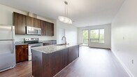 Located at 300 Riverboat Row in Newport, Kentucky, this well-appointed 2-bedroom, 2-bathroom residence offers a thoughtfully designed single-level layout with modern finishes throughout. The open-concept kitchen and living area serves as the heart of the home, anchored by a large center island topped with granite countertops and fitted with an integrated sink and pendant lighting. Rich dark-wood cabinetry, a full suite of stainless steel appliances—including a refrigerator, electric range, and over-the-range microwave—and a subway tile backsplash complete the kitchen. The living area extends naturally from the kitchen, bathed in natural light from expansive windows and a sliding glass door that opens to an outdoor balcony with leafy views. Hardwood-style flooring runs throughout the main living spaces, while plush carpeting adds comfort to both bedrooms. The generously sized primary bedroom features a ceiling fan and a window with outdoor views. The bathrooms are finished with large-format tile flooring, dark granite vanity tops, and rich wood cabinetry. A dedicated laundry area with a stacked washer/dryer and water heater provides added convenience. Two closets offer ample storage throughout the residence.