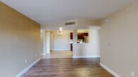 This single-floor residence offers a thoughtfully designed layout that balances open living spaces with functional private areas. The main living room features rich, dark hardwood-style flooring and flows seamlessly into a dining area finished with light tile flooring, anchored by an elegant chandelier overhead. A pass-through window connects the dining space to the kitchen, enhancing the open feel of the interior.

The kitchen is well-equipped with rich dark wood cabinetry, light countertops, and a full suite of black appliances including a gas range, microwave, and refrigerator. Tile flooring carries through the kitchen, which also benefits from a convenient pantry closet.

The bedrooms are finished with warm hardwood-style flooring and feature windows with blinds that allow for natural light. One bedroom includes a ceiling fan for added comfort. The unit is served by two bathrooms — a full bath with a soaking tub and separate shower, dark wood vanity, and tile flooring, as well as a second full bath with a tub-shower combo and matching vanity finishes.

Additional highlights include an in-unit washer and dryer tucked within a dedicated closet, a welcoming entryway with a sliding glass door for outdoor access, and warm neutral wall tones throughout that create a cohesive and inviting atmosphere across the entire space.