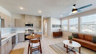 This thoughtfully designed 2-bedroom, 1-bathroom residence offers a functional and modern layout across a single floor. The open-concept kitchen and living area serves as the heart of the home, featuring light wood-tone cabinetry, a full suite of stainless steel appliances including a refrigerator, range, microwave, and dishwasher, and light-toned luxury vinyl plank flooring that flows seamlessly throughout. A cozy dining nook with a round table sits adjacent to the kitchen, while the living room receives generous natural light through large windows and is equipped with a ceiling fan. A dedicated sitting nook with a wall-mounted mini-split unit adds a versatile flex space. Both bedrooms feature plush carpet flooring and ceiling fans; the primary bedroom includes a sliding glass door opening to a private balcony with outdoor views. The second bedroom also features a wall-mounted mini-split HVAC unit and access to a closet. The full bathroom is finished with light wood vanity cabinetry, a white countertop, matte black fixtures, and a bright window. In-unit laundry with washer hookups and built-in shelving provides added convenience. The home's neutral palette and modern finishes create a clean, comfortable living environment throughout.
