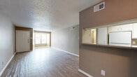 This 1-bedroom, 2-bathroom unit is thoughtfully laid out across a single floor, offering a functional and efficient use of space. The open living area features light-toned laminate wood flooring, neutral beige walls, and a textured popcorn ceiling throughout, creating a consistent and cohesive aesthetic. A large window at the front of the living room allows natural light to fill the space, enhancing its open feel.

The kitchen is designed in a galley style, featuring white cabinetry, granite-look countertops, and white appliances including a refrigerator, electric range, dishwasher, and built-in microwave. A pass-through window with a counter bar connects the kitchen to the living area, improving sightlines and accessibility. Adjacent to the kitchen is a dedicated laundry area with a full-size washer and dryer.

The bedroom is a comfortable size, equipped with a ceiling fan and light fixture, a window with natural light, and access to ample closet storage via two closets. The two bathrooms include a full tub-shower combination with clean white tile surround. Clean white baseboards and trim accent all rooms throughout the unit, and central HVAC vents are present in each room for year-round climate control.