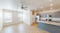 Located at 130 N Cedar St in Centerton, Arkansas, this well-designed one-bedroom, one-bathroom unit offers a comfortable and functional single-floor layout. The open-concept main living area seamlessly connects the kitchen and living room, creating an inviting, airy atmosphere enhanced by light wood-style flooring and recessed lighting throughout.

The kitchen is a standout feature, equipped with stainless steel appliances including a refrigerator with ice maker, range, and microwave. Gray shaker-style cabinetry pairs elegantly with granite countertops, while a teal-accented center island with a built-in sink provides additional workspace and casual dining. A ceiling fan with light fixture adds comfort to the living area, which benefits from a window that brings in natural light.

The spacious primary bedroom features two windows overlooking the surrounding neighborhood, a ceiling fan with lighting, and direct access to a walk-in closet outfitted with double hanging rods and shelving for generous storage.

The bathroom includes a walk-in shower with built-in shelving and wood-style flooring consistent with the rest of the unit. A dedicated laundry area with a stacked washer and dryer is conveniently tucked within the unit. Clean white walls and modern brushed nickel hardware throughout contribute to the home's fresh, contemporary feel.
