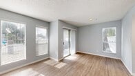 Located at 4610 N Armenia Ave in Tampa, FL, this efficiently designed single-floor unit offers a thoughtful layout across its cozy footprint. The living area is a standout feature, bathed in abundant natural light streaming through multiple windows fitted with blinds and a sliding glass door dressed with sheer curtains that leads to an outdoor space. Light-toned hardwood-style flooring runs throughout, complementing the soft gray walls and textured popcorn ceilings to create a clean, contemporary aesthetic.

The galley-style kitchen is well-equipped, featuring white upper cabinetry, gray lower cabinets, a light countertop with a built-in sink, a stainless steel refrigerator, a dishwasher, and a range. A set of louvered bifold closet doors provides convenient additional storage directly off the kitchen area.

The bathroom is finished in a crisp, all-white palette with a tiled tub-shower combination, a standard toilet, and a vanity topped with a marble-look countertop, offering a clean and functional space.

A hallway connects the rooms, contributing to the unit's efficient flow. White trim and baseboards throughout provide a polished finish, while consistent flooring unifies the space. This unit delivers a bright, move-in-ready environment well-suited for comfortable everyday living.
