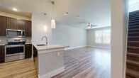 This two-story residence offers two bedrooms and one and a half bathrooms across a generously sized floor plan designed with modern aesthetics and functional living in mind. Wood-style luxury vinyl plank flooring runs throughout the main living areas, creating a cohesive and easy-to-maintain foundation for the space.

The open-concept main level connects the living area directly to the kitchen, which features dark espresso cabinetry, granite-style countertops, a tile backsplash, stainless steel appliances including a range and over-the-range microwave, and a peninsula with pendant lighting and an undermount sink. The living area is bright and airy, benefiting from natural light and a ceiling fan overhead.

The full bathroom includes a dual-sink vanity with dark cabinetry and granite countertops, wood-style flooring, and a separate toilet area. The half bath offers a single vanity with matching finishes. A dedicated laundry room houses a full-size washer and dryer. Bedrooms are well-proportioned, with large windows admitting natural light, and at least one includes a walk-in closet with built-in shelving and hanging rods. Carpet flooring in the closet adds a soft finishing touch.