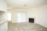 This single-story residence offers a functional and well-organized layout with a neutral color palette throughout. The living room serves as a central gathering space, highlighted by a tile-surround wood-burning fireplace and a large sliding glass door with vertical blinds that allows for natural light. Soft carpeting continues through the living areas and bedrooms, contributing to a warm, comfortable atmosphere.

The galley-style kitchen is efficiently designed with ample cream cabinetry featuring wood trim accents, laminate countertops, a double sink, and white appliances including a coil-top range, dishwasher, and refrigerator. Light tile flooring runs through the kitchen and connects to a dedicated laundry area equipped with an in-unit washer and additional shelving.

The bedrooms are generously sized, each outfitted with ceiling fans, carpeted floors, and windows with blinds that invite natural light. One bedroom includes access to a walk-in closet. A pass-through window connects the kitchen to the main living and dining area, enhancing the open feel of the space.

Two full bathrooms serve the home. The primary bath features a dual-sink vanity with large mirrors and a well-lit vanity bar, while the secondary bath includes a tub-shower combination with tiled surrounds and tile flooring.
