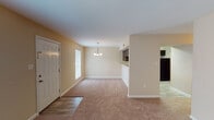 This well-appointed 2-bedroom, 2-bathroom residence in Baton Rouge, Louisiana offers a comfortable and functional single-floor layout. The open-concept living and dining area is carpeted and filled with natural light from a large window, anchored by an elegant chandelier that adds a refined touch. A pass-through counter connects the main living space to the kitchen, which features rich dark cabinetry, light granite-style countertops, black appliances including a range and dishwasher, a double stainless steel sink, and wood-look tile flooring. A hallway leads to the two generously sized bedrooms, each finished with plush carpeting and ceiling fans with integrated lighting. One bedroom includes a walk-in closet and a window with outdoor views, while the other offers a standard closet. Both bathrooms are well-designed, each featuring a full tub-shower combination. One bathroom includes a white vanity with storage and wood-look flooring, while the other is finished with a clean, bright aesthetic. Throughout the unit, warm neutral tones and clean white trim create a cohesive and inviting atmosphere suited for everyday living.