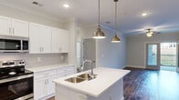 Located at 1025 Hirschfield Dr in Fayetteville, NC, this single-floor residence combines modern design with functional living spaces throughout. Rich hardwood-style flooring flows consistently across the home, complemented by crisp white trim and neutral wall tones that create a clean, cohesive aesthetic.

The kitchen is a standout feature, showcasing white shaker cabinetry, a classic subway tile backsplash, and a spacious center island with a double stainless steel sink and elegant brass pendant lighting overhead. The open layout connects naturally to the living area, which is adorned with crown molding, a ceiling fan, and French doors leading to a private balcony.

The bedrooms are well-proportioned, each equipped with ceiling fans and generous natural light from large windows with blinds. One bedroom offers direct balcony access via a sliding glass door. Closet space is a notable feature, with at least one walk-in closet outfitted with wire shelving systems for organized storage.

The bathrooms are designed with clean, white finishes. One includes a soaking tub with a tiled surround and built-in shelving, while another features a glass-door walk-in shower. Throughout the home, the consistent use of neutral tones, quality fixtures, and thoughtful details contribute to a polished, move-in ready environment.