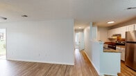 Located at 2920 Cosmo Pl in Fayetteville, NC, this single-floor home offers a well-organized layout with a clean, neutral aesthetic throughout. The living area features warm wood-look flooring, a ceiling fan with light fixture, and windows that invite natural light, creating a bright and comfortable atmosphere. A front entry opens directly into this spacious main living space, which connects seamlessly to the rest of the home.

The kitchen is defined by a half-wall peninsula with granite-style countertops, white cabinetry, and stainless steel appliances including a refrigerator and range. An adjacent dining area is illuminated by an elegant chandelier, adding a touch of style to everyday meals.

A hallway leads to the bedrooms, each finished with plush carpeting, ceiling fans, and windows offering views of the surrounding neighborhood. The primary bedroom includes direct access to a full bathroom and a generous closet with wire shelving. An additional closet provides further storage options.

The bathroom features a full tub and shower combination with a molded surround, a toilet, and wood-look flooring that ties into the home's consistent design language. Textured ceilings are present throughout, complementing the clean white walls. This home offers a functional and comfortable living environment with practical finishes throughout.