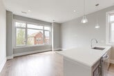 Located in Chicago's vibrant Pilsen neighborhood, this modern 3-bedroom, 2-bathroom home offers a thoughtfully designed single-floor layout. The open-concept living and kitchen area is bathed in natural light from large sliding windows that frame views of the surrounding neighborhood. Light hardwood floors flow throughout, complementing the neutral gray walls and crisp white trim. The contemporary kitchen features sleek, high-gloss cabinetry, a large white quartz waterfall island with an undermount sink, stainless steel appliances including a French door refrigerator, a statement range hood, and pendant lighting that adds warmth to the space. The bathrooms are finished with modern floating vanities, expansive mirrors, chrome fixtures, and tiled walk-in showers. The bedrooms are well-proportioned, with the primary bedroom offering closet access and proximity to a full bath. One bedroom opens directly onto a private balcony equipped with black metal railings, where sweeping views of the Chicago skyline — including Willis Tower — serve as a remarkable backdrop. A hallway connects the living areas to the bedrooms, maintaining a clean and functional flow throughout this stylish urban home.