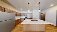 Located at 2141 North McCarthy Road in Appleton, Wisconsin, this well-designed single-floor unit offers a thoughtful layout across one bedroom and two bathrooms. The open-concept kitchen and living area serves as the heart of the home, showcasing warm wood cabinetry, stainless steel appliances, and a generous center island with a white countertop and undermount sink, illuminated by stylish globe pendant lights. Light hardwood flooring flows throughout the main living spaces, complementing the clean, neutral palette of the walls and trim.

A long, well-lit hallway connects the living areas to the private spaces, with a stacked washer and dryer conveniently tucked into a dedicated closet along the corridor. The spacious primary bedroom is finished with plush carpet, a ceiling fan, a wall-mounted mini-split climate control unit, and a walk-in closet with built-in shelving. A window provides natural light and ventilation. Two bathrooms serve the unit, one featuring hardwood-style flooring and clean modern fixtures.

The attached garage offers a concrete-floored space ideal for secure parking or additional storage. Baseboard heating throughout and a modern mini-split system ensure year-round comfort in this move-in-ready Appleton residence.