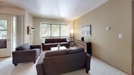 Located at 3000 W Howard Ave in Milwaukee, Wisconsin, this two-bedroom, one-bathroom residence offers a practical and comfortable single-floor layout. The living room serves as the heart of the home, featuring neutral warm-toned walls, plush carpeting, and a large window fitted with vertical blinds that allow generous natural light and views of the surrounding greenery. The kitchen is clean and efficient, outfitted with white cabinetry, a gas range, a full-size refrigerator, a built-in sink, and light tile flooring — providing all the essentials in a streamlined galley-style arrangement. The primary bedroom is a well-proportioned retreat, offering carpeted flooring, a large window overlooking outdoor greenery, and a full-width sliding wood-panel closet for substantial storage. The second bedroom accommodates two beds comfortably and also features a wide window with natural views, a sliding closet, and soft carpet underfoot. The full bathroom includes a tub-shower combination with tiled surround, a white vanity with under-cabinet storage, and a wall-mounted mirror. A hallway connects the rooms, contributing to a logical and easy-to-navigate floor plan throughout the residence.