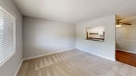 Located at 306 Estes Drive in Carrboro, NC, this single-floor, two-bedroom, one-bathroom residence offers a practical and well-organized layout. The living room greets you at the entry, featuring neutral-toned carpet, soft gray walls, a textured ceiling, and a front-facing window that brings in natural light. A pass-through counter seamlessly connects the living area to the kitchen, which is equipped with stainless steel appliances — including a range, microwave, and refrigerator — white cabinetry, dark countertops, and hardwood-style flooring. A ceiling fan with integrated lighting adds comfort to the kitchen and adjoining dining space. Both bedrooms are carpeted and finished with the same understated gray palette, offering a calm and neutral atmosphere. The primary bedroom provides a generous amount of floor space and includes a window with an exterior view. The second bedroom is similarly sized with its own window for natural light. The full bathroom features a tub and shower combination with a curved curtain rod. A dedicated closet provides additional storage. Clean finishes and a cohesive neutral color scheme throughout give this residence a move-in-ready appeal.