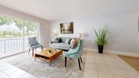 Suite 207 is a thoughtfully designed single-floor residence offering two bedrooms and two bathrooms. Light-toned tile flooring flows consistently throughout the space, lending a cohesive and clean aesthetic. The living area is airy and inviting, featuring soft neutral walls, large windows that draw in natural light and offer outdoor views, and ample room for relaxed seating arrangements. The kitchen is well-equipped with rich dark wood cabinetry, granite countertops, a mosaic tile backsplash, stainless steel appliances including a Maytag range and wall oven, and a pass-through window that connects to the adjacent living space. The primary bedroom is generously proportioned, featuring a tufted upholstered headboard and direct access to an en-suite bathroom with a walk-in shower clad in large-format beige tile and polished chrome fixtures. The second bedroom maintains a calm, neutral palette with tile flooring and natural light. Its adjacent bathroom includes a combination tub and shower with matching tile surround, a dark wood vanity, and a framed mirror. Together, the rooms create a cohesive, comfortable living environment with consistent finishes throughout.