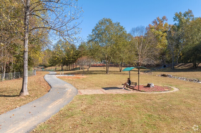 Shaded park benches offer shade alongside the paved walking trails of Dacula.