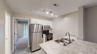 Located at 1755 Ploughboy Ln in Winston Salem, NC, this single-floor unit offers a well-designed layout with a consistent neutral color palette and a blend of hard and soft flooring surfaces throughout.

The kitchen is a functional highlight, equipped with stainless steel appliances including a full-size refrigerator and an electric range. White shaker-style cabinetry provides ample storage, while granite-look countertops add a polished finish. A double basin stainless steel sink sits at the peninsula, and track lighting overhead ensures the space is well lit. Light wood-look tile flooring ties the kitchen together seamlessly.

The living and entry areas feature the same durable wood-look tile flooring, neutral warm-toned walls, and ceiling fans with integrated lighting. A sliding glass door fitted with vertical blinds opens to allow natural light into the bedroom, which is finished with plush carpeting for added comfort.

The bathroom is cleanly appointed with a granite-look vanity countertop, an undermount sink with brushed nickel fixtures, a large mirror with overhead lighting, and a shower-tub combination. The overall design is cohesive and move-in ready, offering a practical and comfortable living environment in a convenient Winston Salem location.
