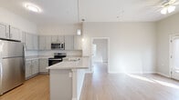 This well-designed 2-bedroom, 2-bathroom residence at 4691 Hall Rd in Columbus, Ohio offers a clean, modern aesthetic throughout its single-floor layout. Light hardwood flooring runs continuously across all rooms, creating a cohesive and bright atmosphere. The open-concept kitchen serves as the heart of the home, outfitted with gray shaker-style cabinetry, granite-look countertops, a peninsula with an integrated sink, and a full suite of stainless steel appliances including a refrigerator, range, and over-the-range microwave. Pendant lighting above the peninsula adds a polished finishing touch. The kitchen flows naturally into the living area, enhancing the sense of openness. Both bedrooms are well-proportioned and filled with natural light from multiple windows fitted with white blinds. The primary bedroom features a dedicated walk-in closet with built-in wire shelving and hanging rods, offering generous organization capacity. Each bathroom is finished with gray vanity cabinetry, white countertops, and a tub-shower combination, maintaining the home's clean, neutral palette. A central hallway connects all rooms efficiently, and the overall design emphasizes simplicity, functionality, and modern comfort throughout.