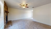 This single-story residence features a practical and well-organized floor plan with two bedrooms and two bathrooms. The spacious living room serves as the heart of the home, highlighted by a striking stone-surround fireplace with a wood mantel, plush carpeting, a textured ceiling, and a ceiling fan with integrated lighting. Natural light filters in through blinds-covered windows, enhancing the bright, neutral atmosphere throughout.

The kitchen is designed for efficiency, featuring white cabinetry, dark granite-style countertops, wood-look flooring, and black appliances including a refrigerator and range. A galley-style layout maximizes counter and storage space.

The primary bedroom is a comfortable retreat with carpet flooring, a ceiling fan, and direct access to a walk-in closet equipped with built-in shelving and hanging rods. The second bedroom also features carpet flooring and a ceiling fan. Both bathrooms are cleanly appointed; one includes a wide vanity with white cabinetry, a dark countertop, a large mirror with overhead lighting, and wood-look flooring.

A hallway connects the main living areas to the bedrooms and bathrooms, ensuring a logical and convenient flow throughout this well-maintained single-floor home.