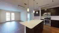 This single-floor residence offers a thoughtfully designed open-concept layout that seamlessly connects the kitchen, dining, and living areas. The kitchen is a standout feature, showcasing rich dark espresso cabinetry that extends to the ceiling, a generous quartz-topped island with pendant lighting overhead, and a full suite of stainless steel appliances including a range, microwave, dishwasher, and refrigerator. A classic white subway tile backsplash adds a clean, contemporary contrast, while warm hardwood-style flooring flows throughout the main living areas, enhancing the cohesive aesthetic. Track lighting throughout the kitchen and living areas provides ample illumination and a modern touch. The living space is generously proportioned, featuring double closet doors and a large window that invites natural light. The bedrooms are carpeted for comfort, each equipped with ceiling fans and windows fitted with blinds that offer both privacy and outdoor views. The bathrooms continue the home's modern palette, featuring wood-look tile flooring, dark vanity cabinetry, a soaking tub, and well-organized layouts. The overall ambiance is clean, contemporary, and move-in ready, combining functional design with stylish finishes throughout.
