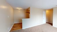 This single-story apartment offers a blend of functionality and comfort. The open floor plan seamlessly connects the living areas, creating a sense of spaciousness. The space features a mix of flooring materials, with rich hardwood in the main living area and kitchen, transitioning to plush carpeting in the bedrooms for added comfort.

The galley-style kitchen is equipped with wooden cabinetry, providing ample storage space. It includes essential appliances such as a refrigerator and stove, with butcher block countertops adding a touch of warmth to the space. The living area is partially separated from the kitchen by a half-wall, maintaining an open feel while defining distinct spaces.

Multiple windows throughout the apartment allow for generous natural light, enhancing the warm, neutral color palette of the walls. The bedrooms are spacious, with large windows and closet space. The bathroom features classic white tiling and a full-size bathtub with a shower.

The apartment's layout is efficiently designed, maximizing usable space while maintaining a comfortable flow between rooms. Overall, this residence offers a practical and inviting living environment, suitable for various lifestyle needs.
