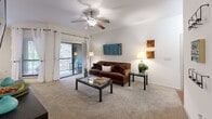 Located at 5803 UTSA Boulevard in San Antonio, Texas, this well-designed 2-bedroom, 2-bathroom residence offers a thoughtful single-level layout that maximizes both comfort and functionality. The living room serves as the heart of the home, featuring plush carpeting, a ceiling fan, a built-in bookshelf nook, and large sliding glass doors that open onto a private balcony overlooking lush, mature trees. Natural light flows freely throughout the space, creating a bright and welcoming ambiance.

The galley-style kitchen is outfitted with warm wood cabinetry, dark granite-style countertops, hardwood flooring, and black appliances, providing ample storage and workspace. It connects seamlessly to the dining area, which also enjoys views of the surrounding greenery.

The primary bedroom is a comfortable retreat, highlighted by a ceiling fan, large windows framing serene outdoor views, and plush carpeting. A second bedroom, two closets, and a hallway complete the private quarters. Both bathrooms are functional and well-proportioned. Throughout the residence, a consistent design palette of neutral tones and warm wood accents creates a cohesive and inviting atmosphere suited for everyday living.