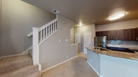 This two-story residence at 1104 Hidden Ridge in Irving, Texas offers a well-designed layout across two levels, connected by a carpeted staircase accessible from the entry. The main level features an open-concept living area with plush carpet, crown molding, and a classic fireplace framed in white. Large windows and a glass-panel door flood the space with natural light while providing views of the surrounding exterior. The kitchen is outfitted with dark wood cabinetry, granite countertops, a subway tile backsplash, and stainless steel appliances including a refrigerator, electric range, and over-the-range microwave. A granite-topped island with a sink adds additional workspace and storage. The bathroom showcases dark espresso cabinetry with granite countertops, dual mirrors, and a soaking tub with shower combination set against wood-look flooring. Bedrooms are carpeted and feature ceiling fans, generous windows, and ample closet space — including a mirrored sliding-door closet in one room. An in-unit washer and dryer are also accessible. Neutral tones, textured walls, and consistent finishes throughout create a cohesive and comfortable living environment throughout both floors.